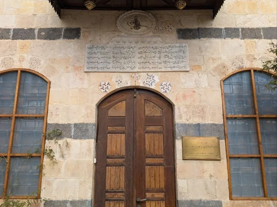 The carved wooden canopy and doors of the tomb of Shaykh Khalid al-Naqshbandi in Damascus, an Ottoman tughra and a Persian inscription set in the banded stone above