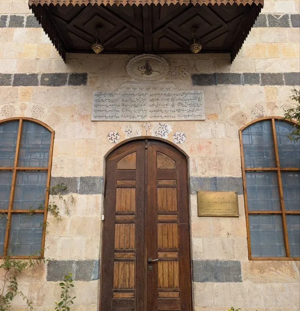 The carved wooden canopy and doors of the tomb of Shaykh Khalid al-Naqshbandi in Damascus, an Ottoman tughra and a Persian inscription set in the banded stone above