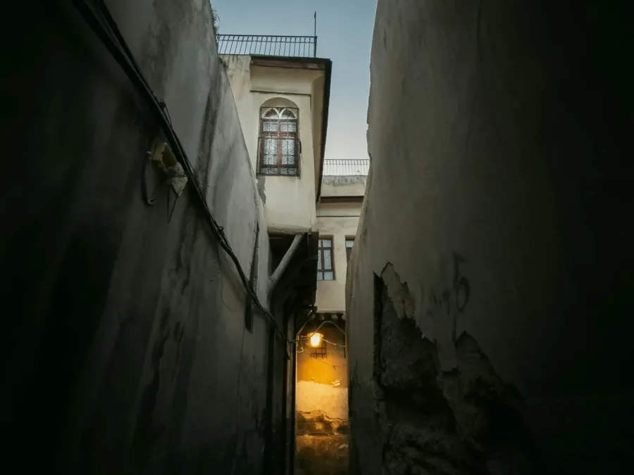 A narrow lamplit alley in the Old City of Damascus at dusk