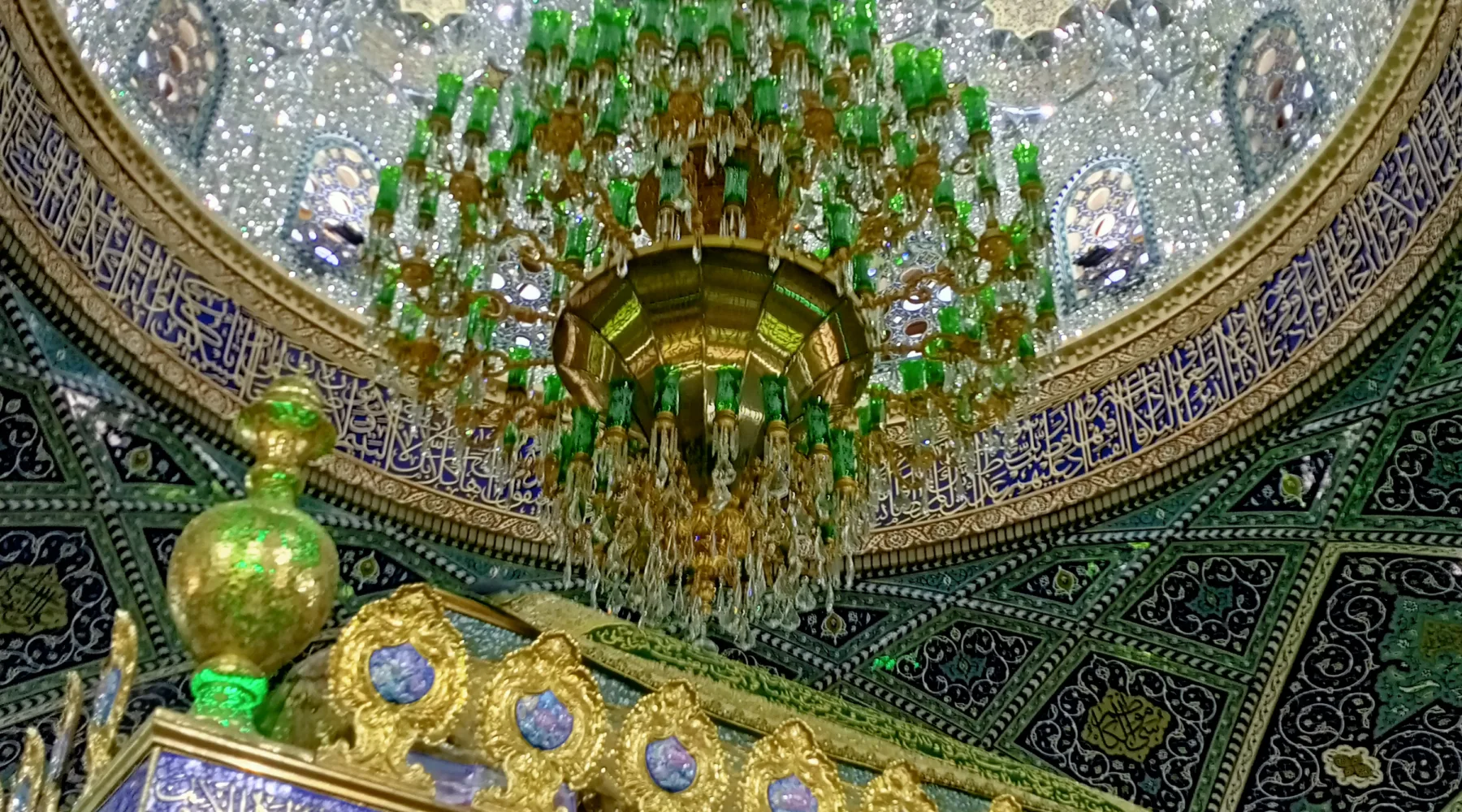 The mirrored dome and green glass chandelier above the gilded tomb screen in the shrine of Sayyida Ruqayya, Damascus