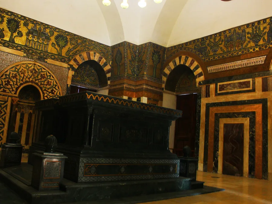 The dark marble cenotaph of Sultan Baybars beneath a band of gold mosaic in the Zahiriyya madrasa, Damascus
